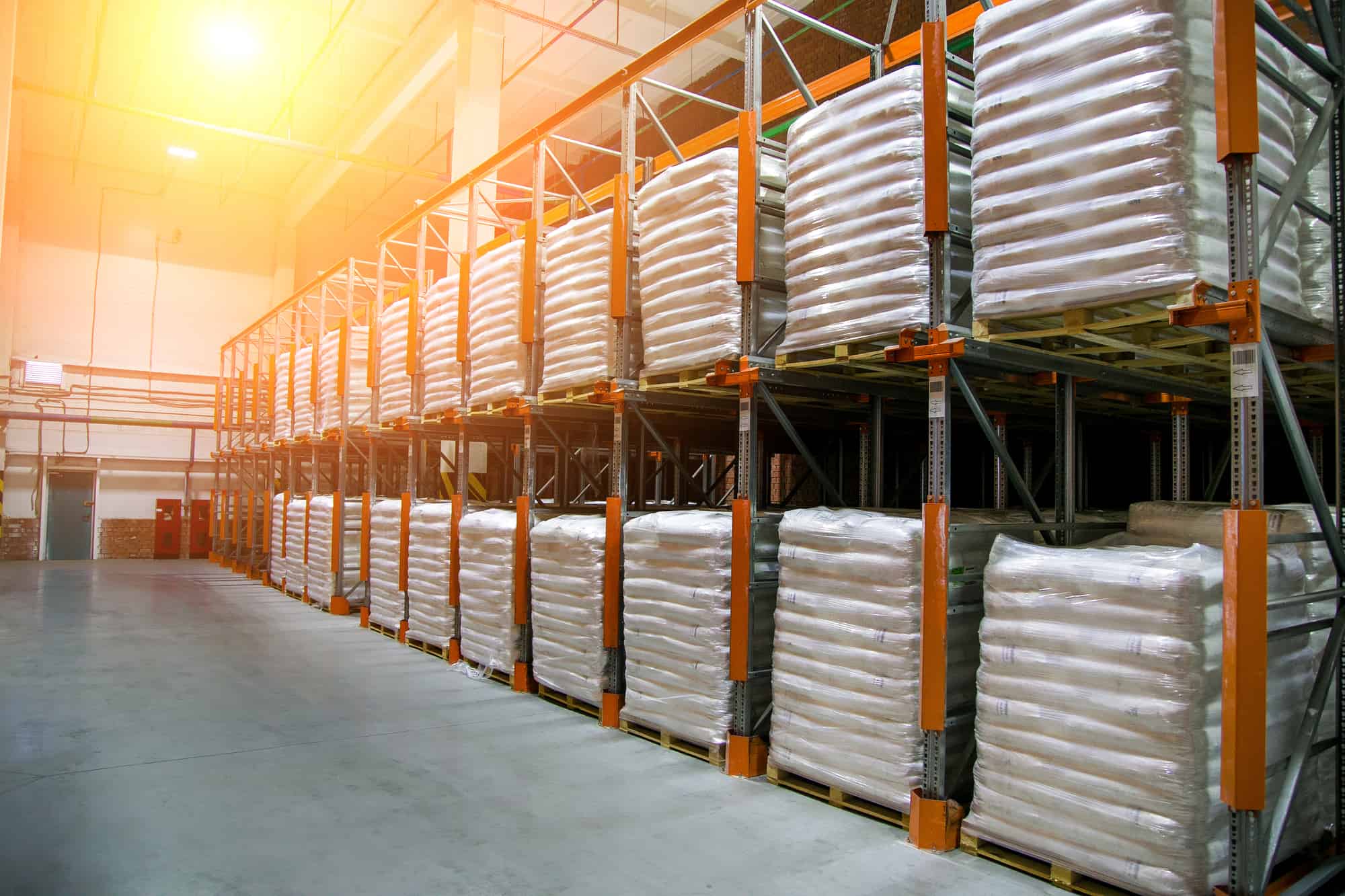 hangar warehouse with rows of shelves with white polyethylene ba